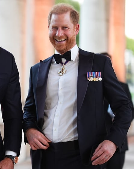 Laughing man with auburn hair and beard in bow tie and black blazer with medals