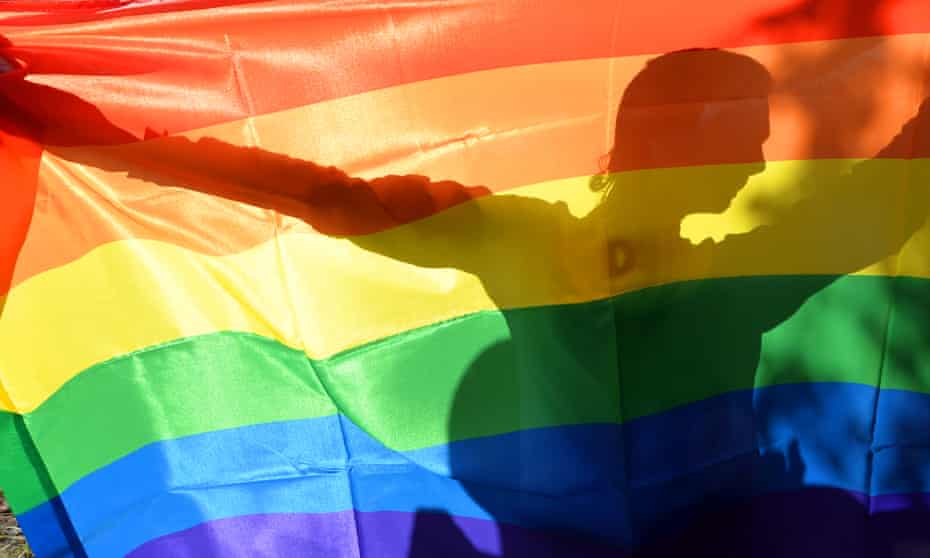 A gay activist holds up a rainbow flag … 