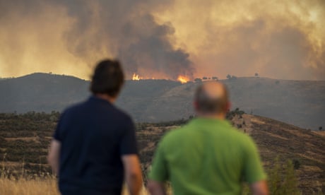 Two onlookers watch burning hills
