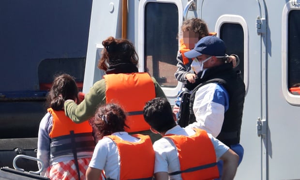 A Border Force officer escorts a young family thought to be migrants from a Border Force vessel after they were brought into Dover, Kent.