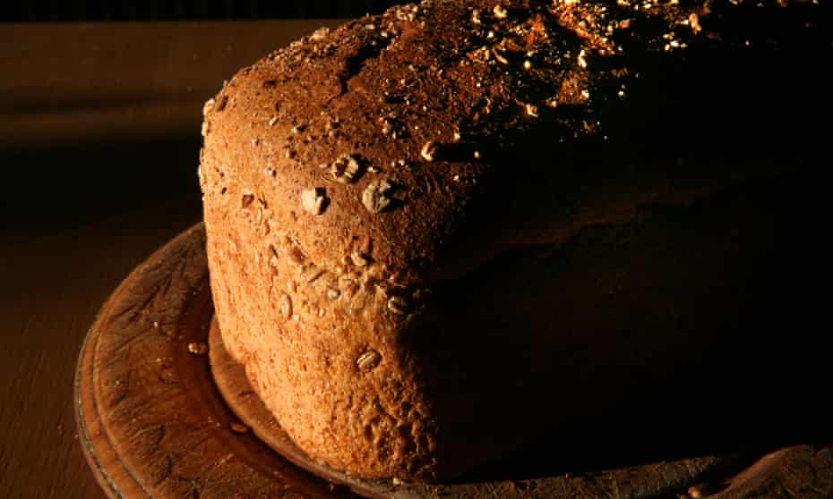 A loaf of multigrain bread on a breadboard.