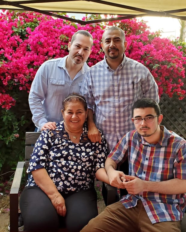 four people posing for a photograph in which to men are standing at the back and a woman and a young man are sitting in front of them