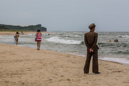 A man in military uniform watches over beachgoers near Wonsan