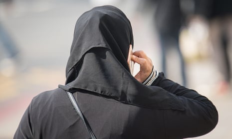 A Muslim woman wearing a hijab talks on her mobile phone.