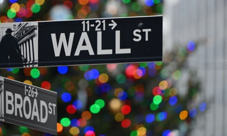 the Wall Street sign at the New York Stock Exchange with Christmas tree lights in the background
