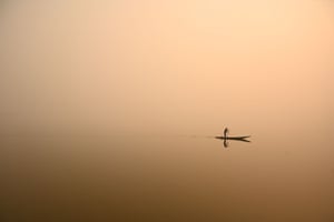 A man steers a boat across Dal Lake in Srinagar, Kashmir, amid a thick blanket of fog
