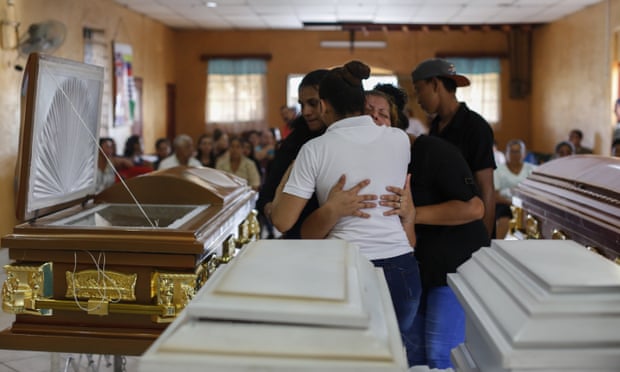 Friends and family mourn the body of two infants Matías and Daryelis Velásquez during the wake for six members of the family who died after their home was torched on 16 June.