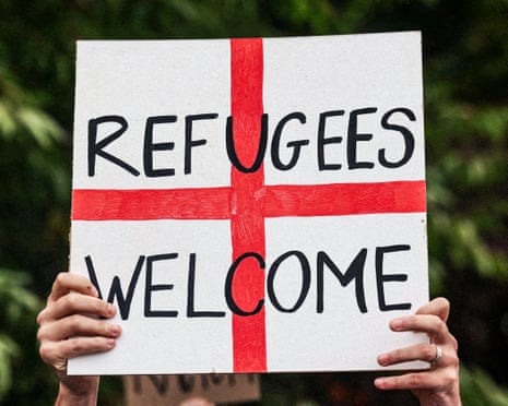 A person holds an England flag banner that reads: 'Refugees welcome'