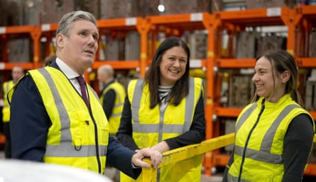 Lisa Nandy and Keir Starmer, in hi-vis vests, talk to a worker in a warehouse