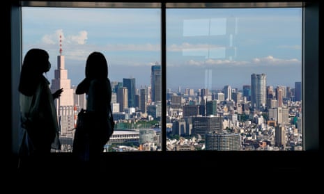 People look at the Tokyo skyline from a government building in the city