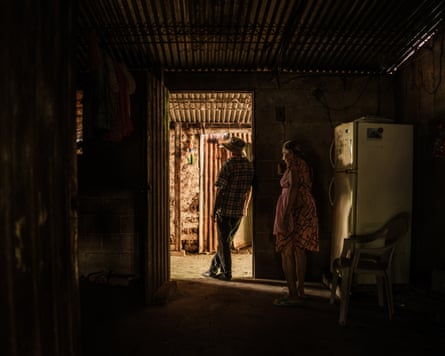 A farmer from Cabañas, who wished to remain anonymous, leans against a doorframe. Behind him, his mother-in-law moves to turn on the light.