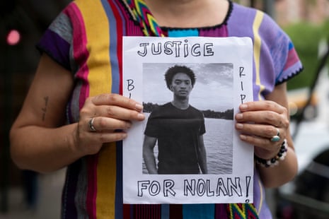a person holds a picture of a teenage boy with 'justice for Nolan' written on it