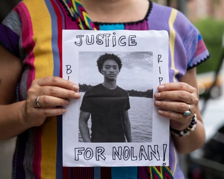 A person holds a small banner with a picture of Nolan Wells and the words: ‘Justice for Nolan’ during a news conference.