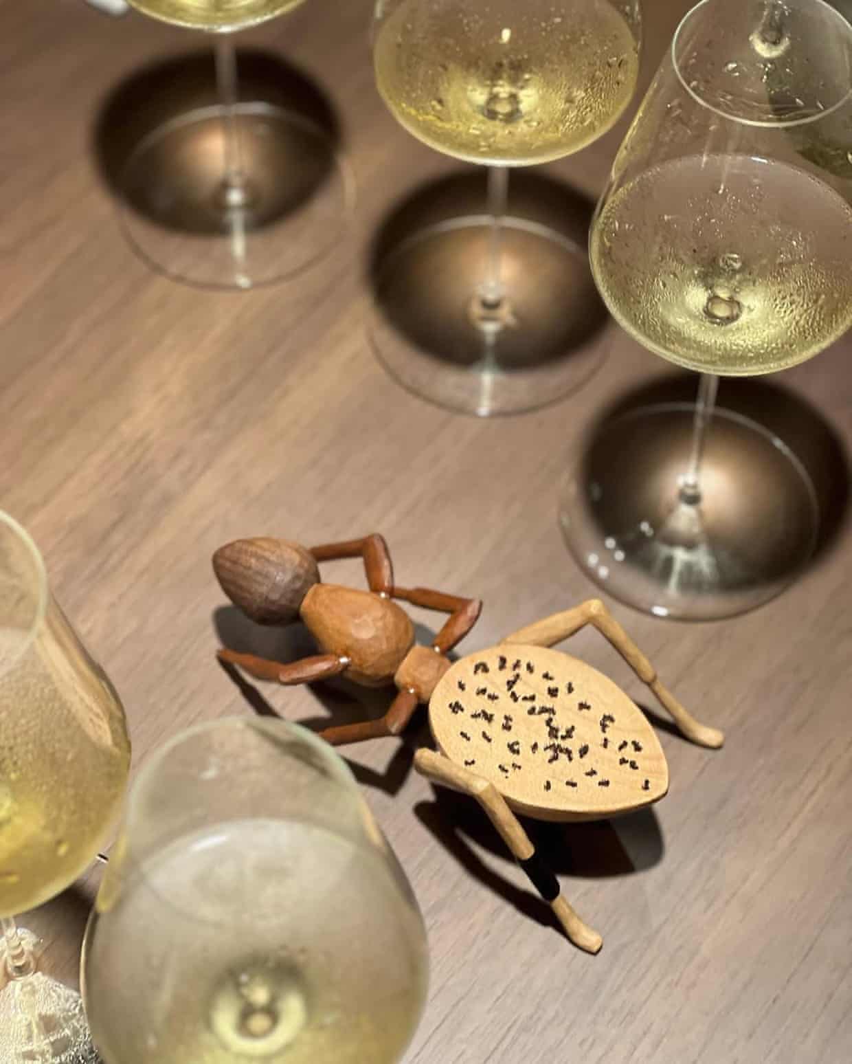 The ants laid out on a wooden ant decoration on a table surrounded by wine glasses