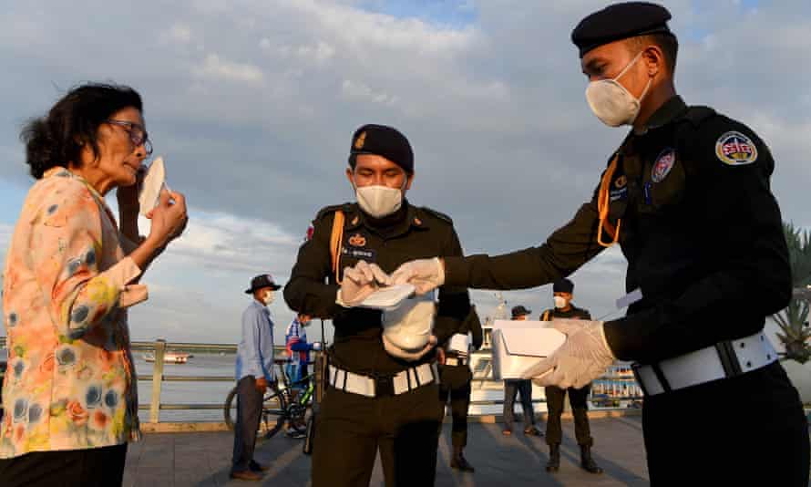 Military police officers hand out free face masks to people, amid concerns over a spread of the Covid-19 coronavirus at a park in Phnom Penh