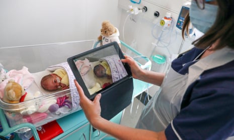 A maternity nurse makes a video of a newborn baby.