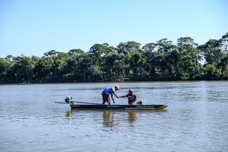 Dois pescadores em um pequeno barco em um rio largo com floresta tropical ao longo da margem