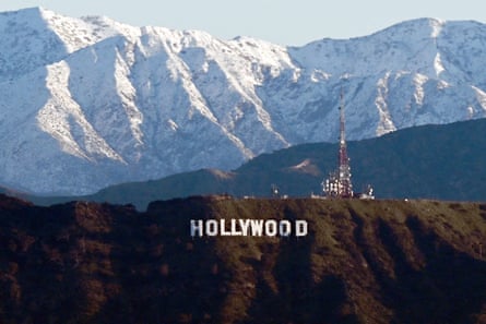 Snow capped mountains on the skyline behind a view of the Hollywood sign following heavy rain from winter storms.