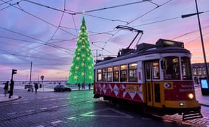 A tram drives past the fully lit Christmas tree in the almost deserted Praça do Comercio,