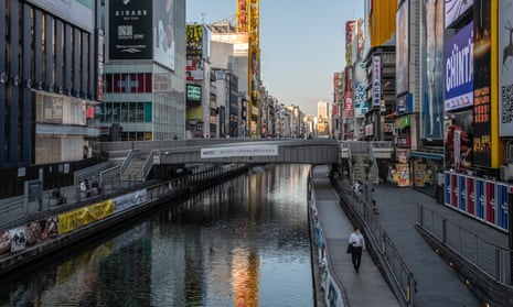 A man wearing a face mask walks alongside the canal in osaka, japan