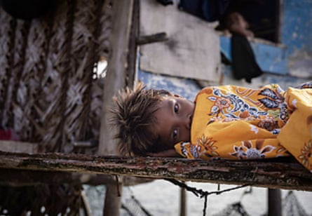 A Bajau child lying on the decking of her houseboat.