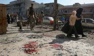 Iraqi soldiers inspect damage from a roadside bomb.