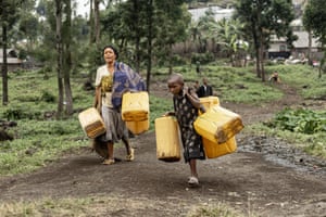 People carry yellow jerrycans along a dirt path