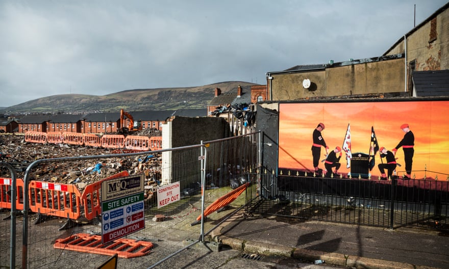 “Two men bow their heads in honour of slain loyalist paramilitaries” ... murals line the peace walls in the Shankill Road area of West Belfast.