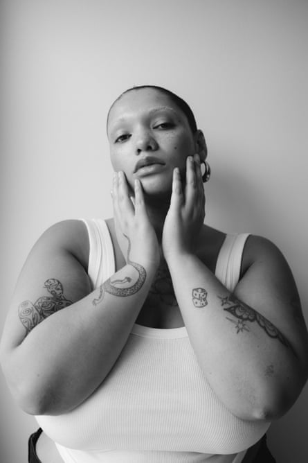 Plus size model Skye Standley with her hair scraped back in a white vest - black and white from waist up with hands cradling her chin
