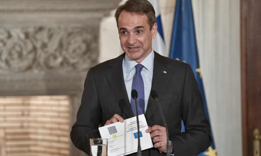 Greece’s prime minister, Kyriakos Mitsotakis, displays the proposed EU digital Covid passport in Athens