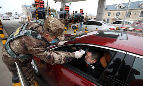 A Chinese security forces member checks the body temperature of a driver at a road toll gate in Wuhan on Thursday.