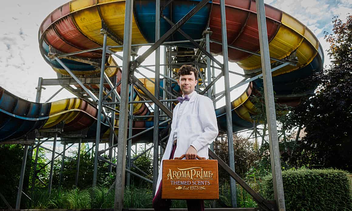 A man stands in front of a rollercoaster.