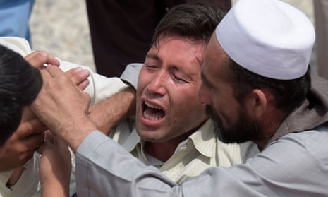 A victim’s relative is comforted after Saturday’s attacks in Kabul