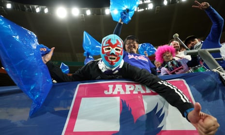Japan fans, some wearing masks and wigs cheer for their team in the stadium ahead of kick off in their match against Norway.