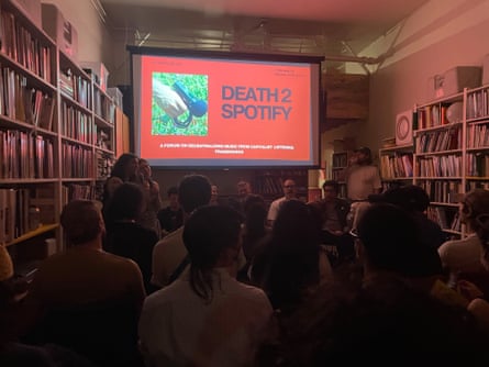 People sit in a library and watch as a panel of speakers gives a presentation