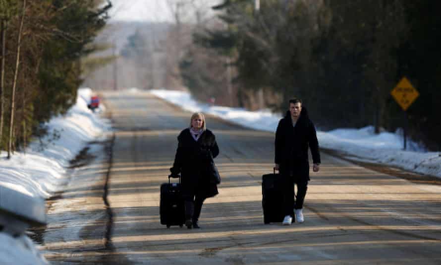 People walking with their luggage on Roxham Road before crossing the US-Canada border.