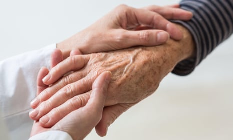 Younger woman’s hands holding the hand of an older person.