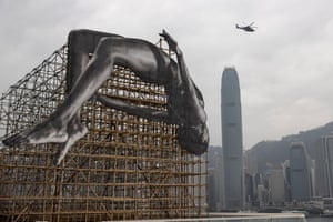 Hong Kong. A helicopter flies near the artwork Giants: Rising Up at Harbour City. The 12-metre x 12-metre installation by the French artist JR depicts a larger-than-life high jumper bending in midair, adjacent to Victoria Harbour