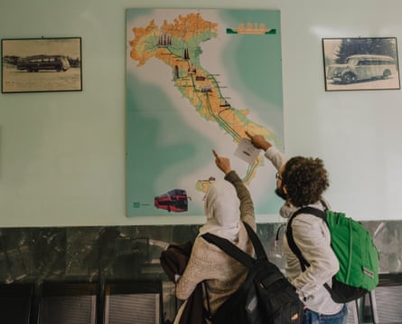 Somar and Lubna pointing at a map of Italy in the bus station area in Catania.