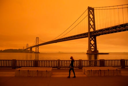 A woman walks under an orange smoke-filled sky in San Francisco on 9 September when more than 300,000 acres were burning across the north-western state including 35 major wildfires.