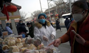 A woman wearing a face mask buys food from a stall set up by a restaurant outside its outlet in Beiing, China.