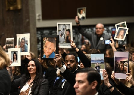 People in suits hold up pictures of children