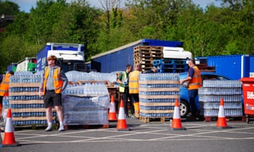 People wearing hi-vis vests standing next to pallets of bottled water