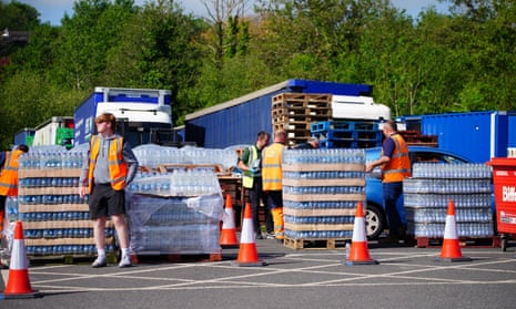 People wearing hi-vis vests standing next to pallets of bottled water
