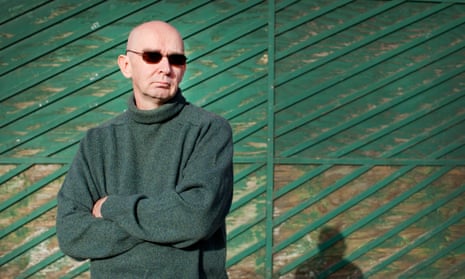 Boris Karpichkov in a green sweater and sunglasses standing in front of a green fence.