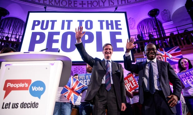 The two politicians wave in front of a crowd in a church and sign saying 'put it to the people'