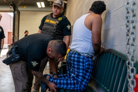 Police shackle a man kneeling on a bench