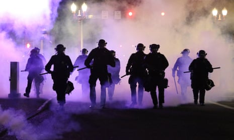 Police officers walk enveloped by teargas in Portland in March.