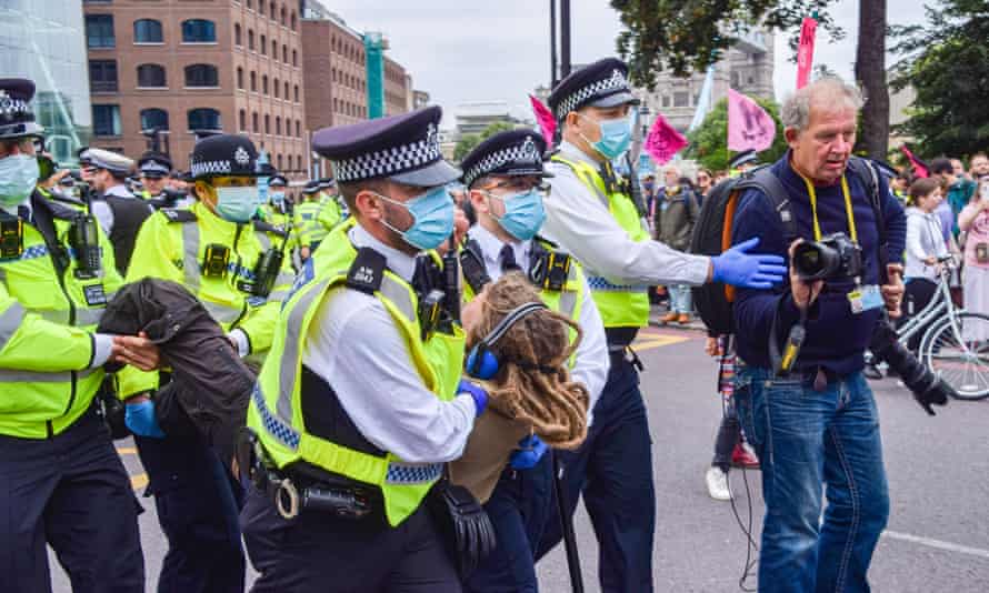 Police officers arrest a protester during an Extinction Rebellion demonstration in Tower Hill, London