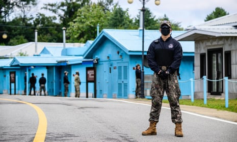 A South Korean soldier (R) and UNC (United Nations Command) soldier (background, in green) stand guard near the military demarcation line separating North and South Korea at the DMZ